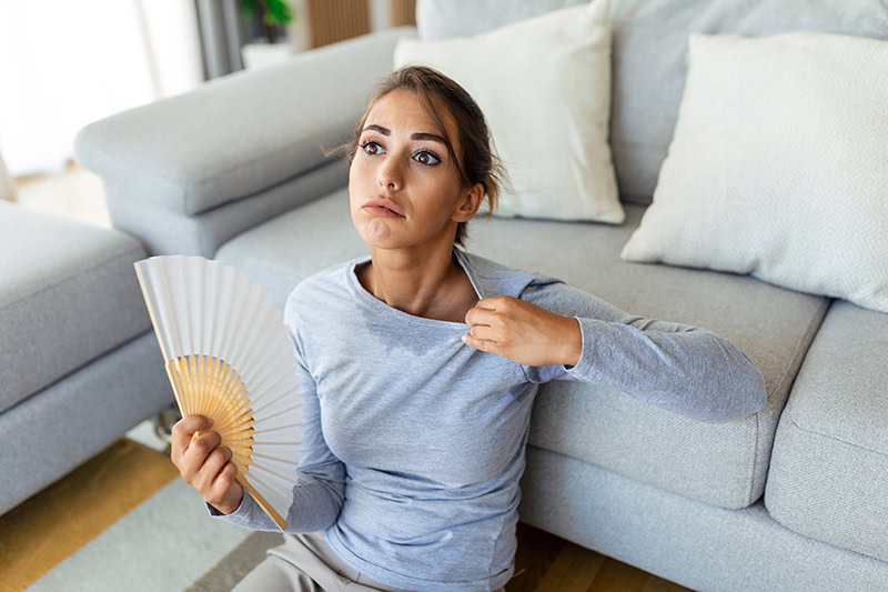 A woman appears uncomfortable due to needing more effiicent HVAC performance.