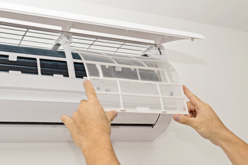 What Maintenance Is Needed for a Ductless System? Photo of someone changing a filer in an AC unit mounted on a wall.