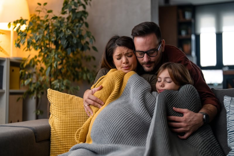 Family freezing at home because of an expensive heating during cold winter. Trying to warm themselves up. Inflation. Expensive bills.