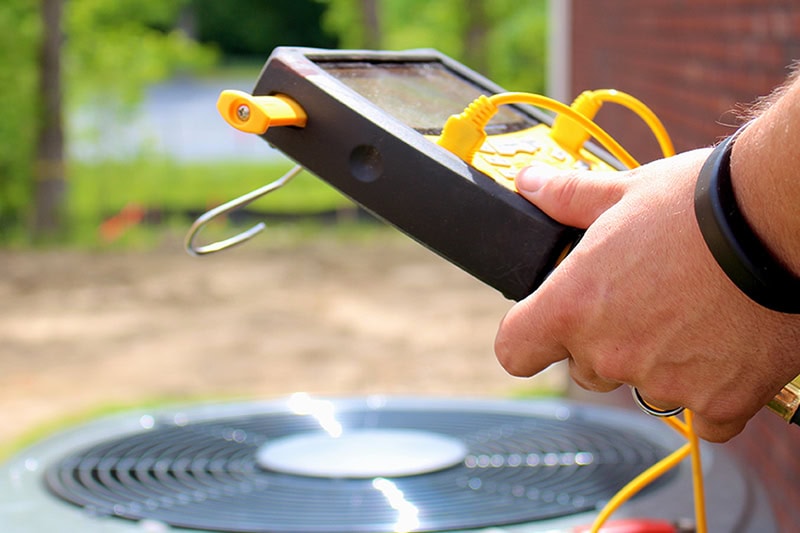 What Does NATE-Certified Mean? Photo of a technician holding a device to test HVACs