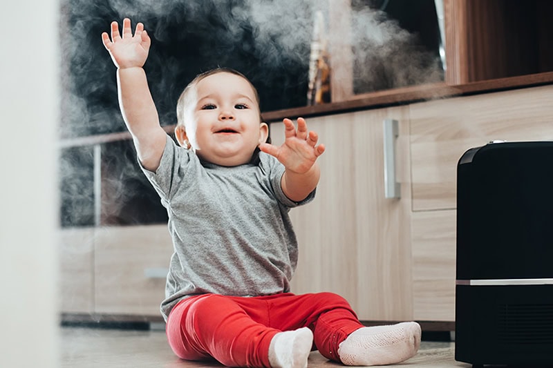 Indoor humidity is important for comfort. It makes all the difference in how comfortable your home is while you are relaxing, sleeping, and keeping you or your family healthy. Photo of a baby playing with humidifier mist.